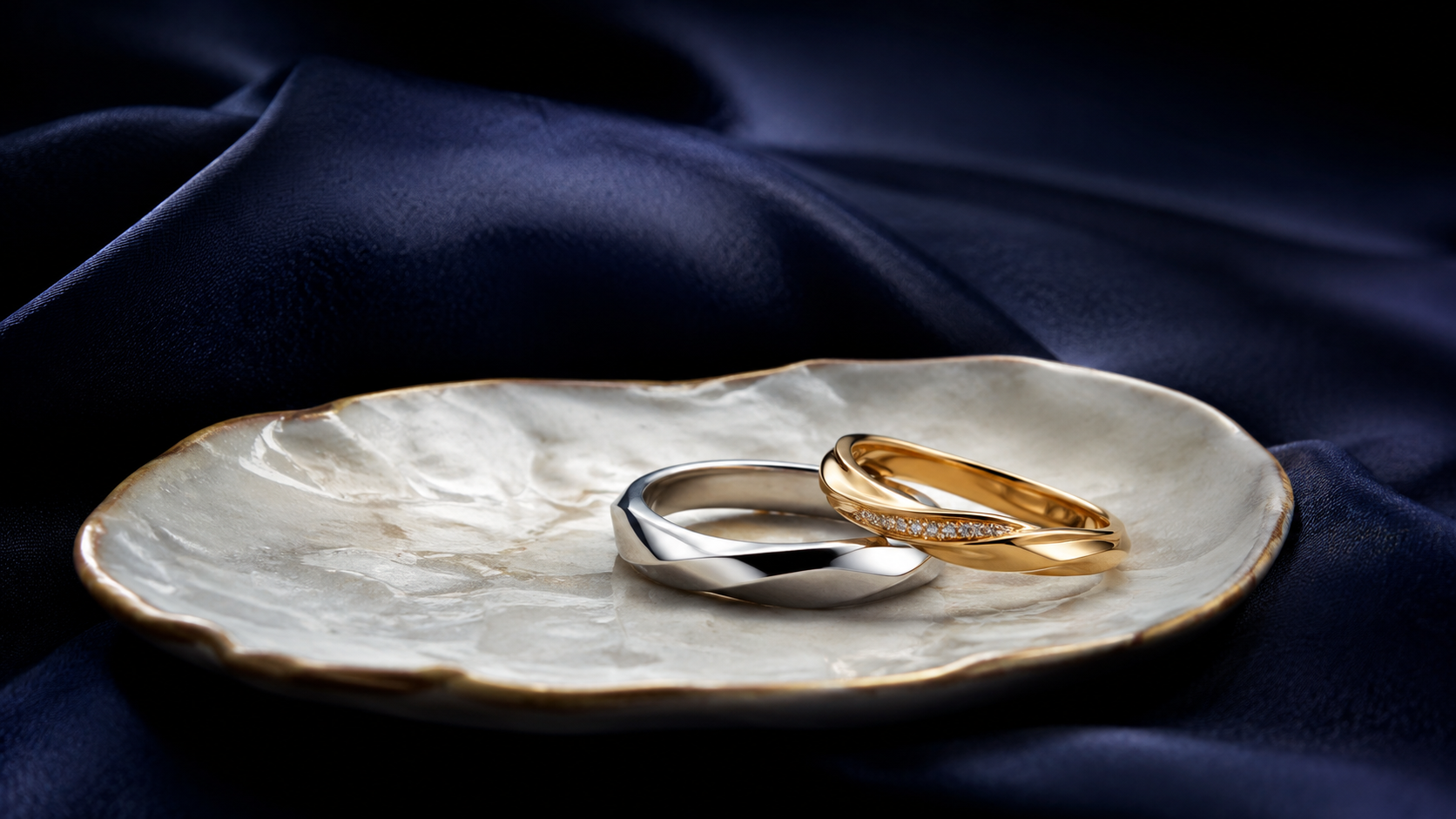 A white gold ring and a yellow gold ring resting on a pale ceramic dish